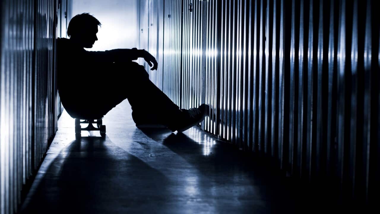 Young person sitting alone on their skateboard.