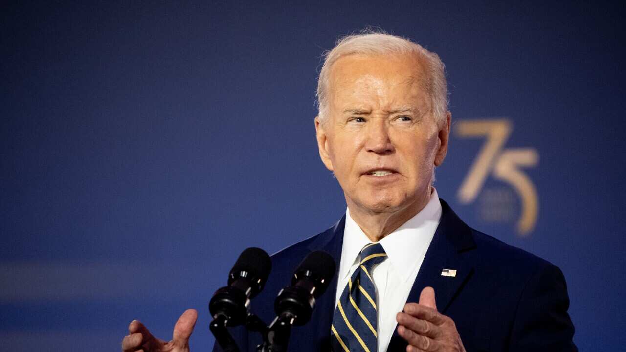 Joe Biden gestures as he stands at a podium with a stern expression on his face