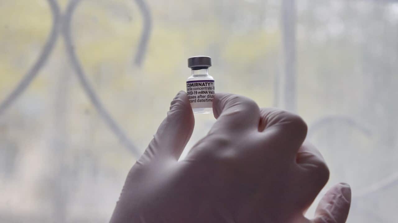 A health worker holds a vial containing Pfizer Covid-19 vaccine at a vaccination center