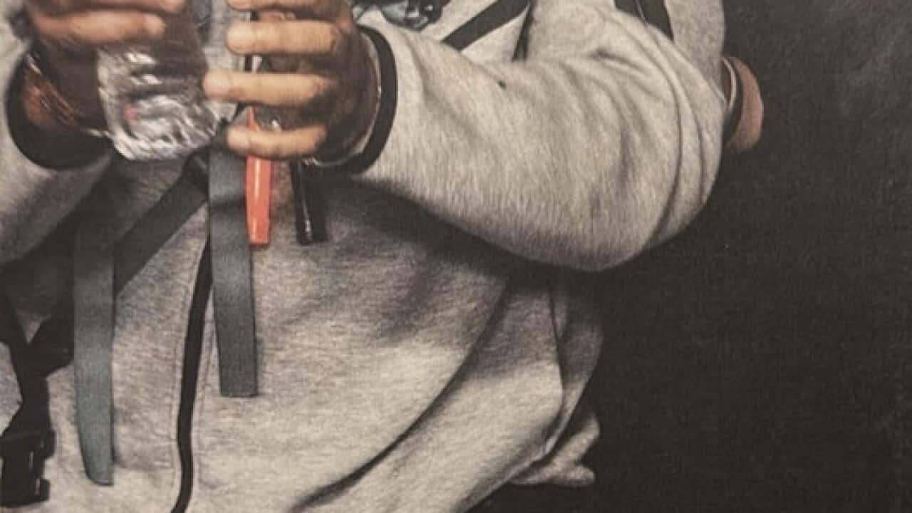 A man in a grey tracksuit with a blindfold and headphones on 