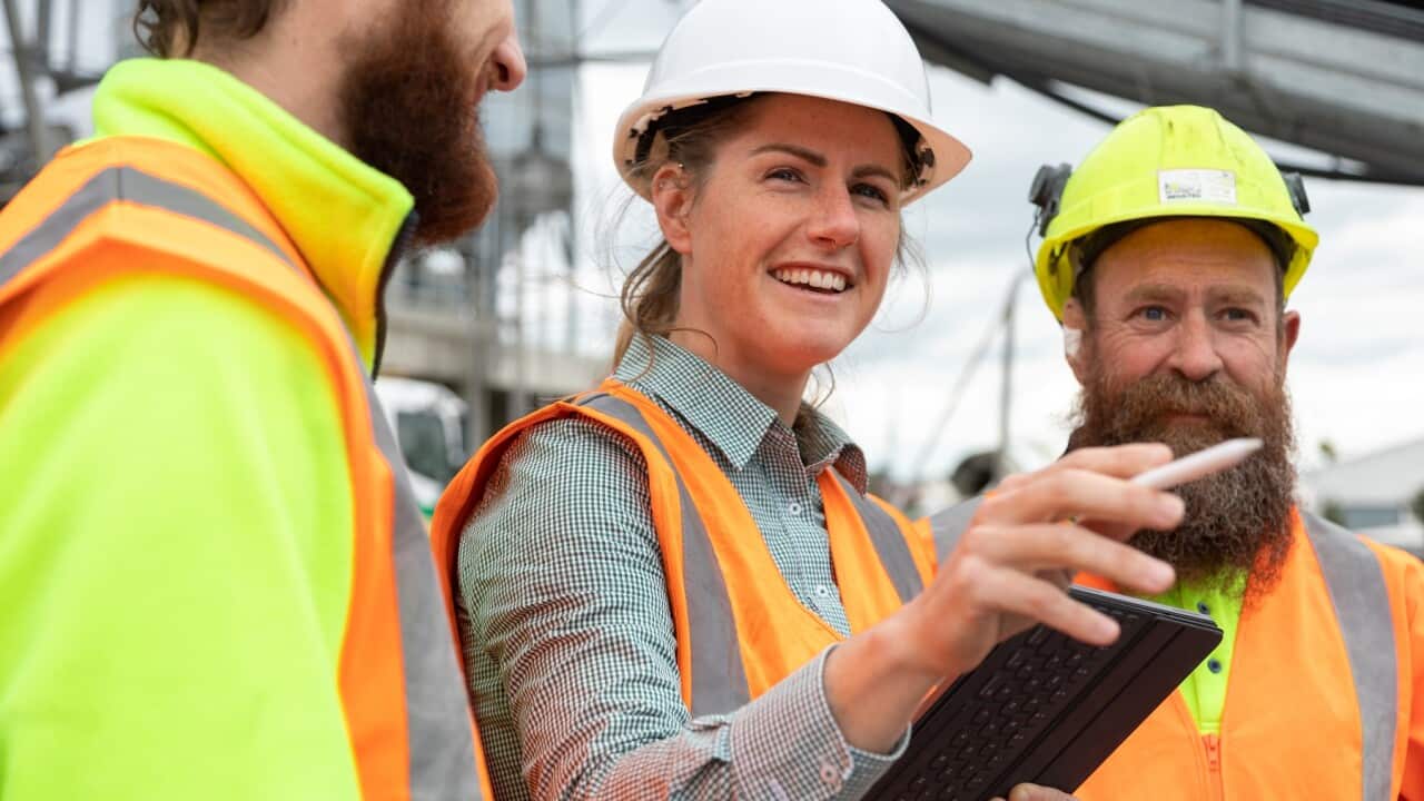 A woman in a leadership role talks to her co workers on a construction /manufacturing site