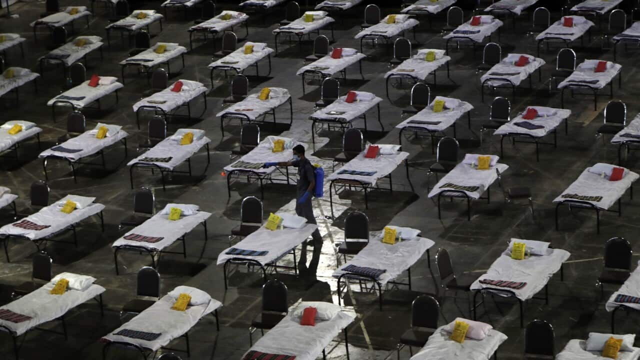 A civic worker sprays disinfectant on beds at a special temporary hospital facility for COVID-19 patients in Mumbai, India, Friday, April 10, 2020.