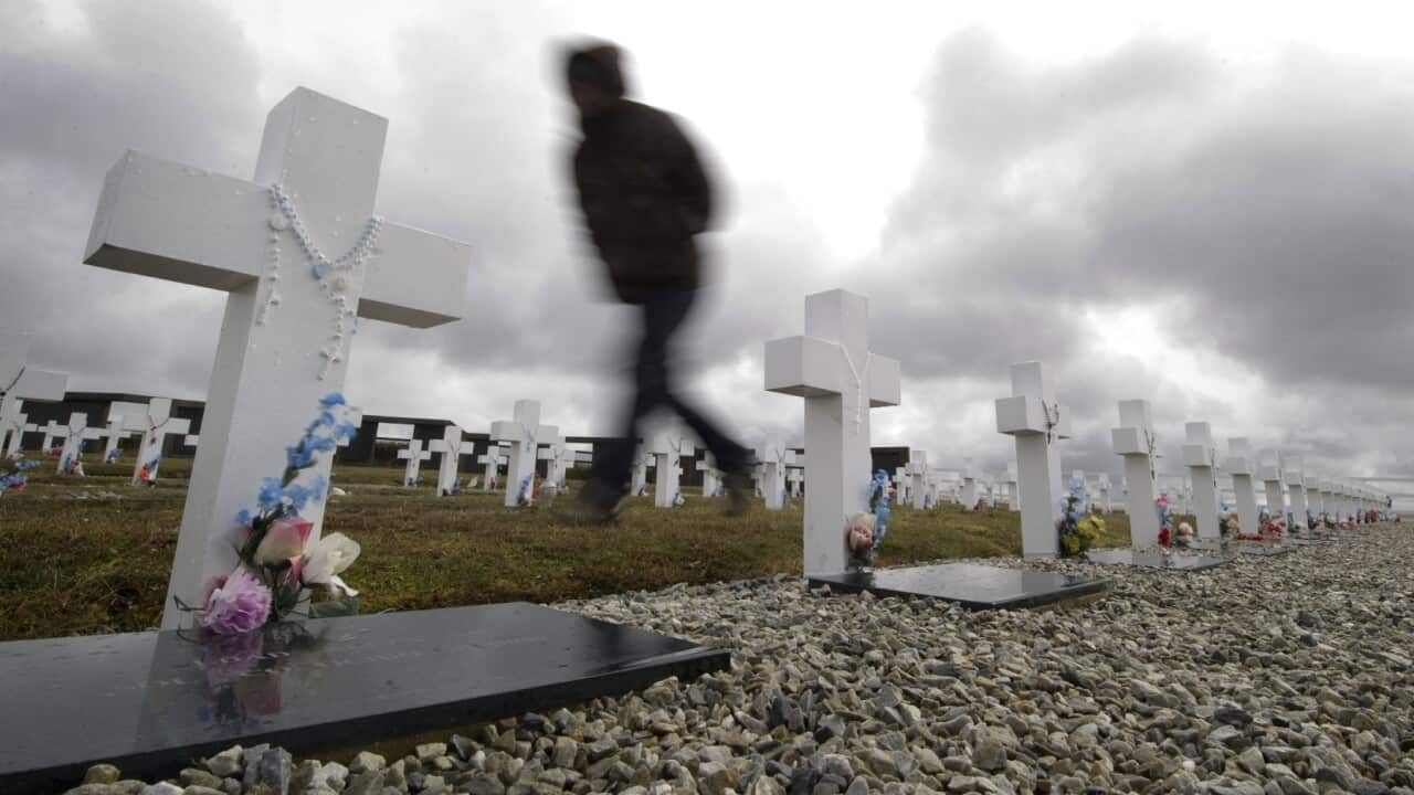 A tourist walks among tombstones at Argentine Darwin cementery, in the Falkland Islands