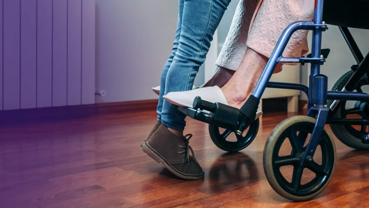 Feet of a person standing over a person in a wheelchair