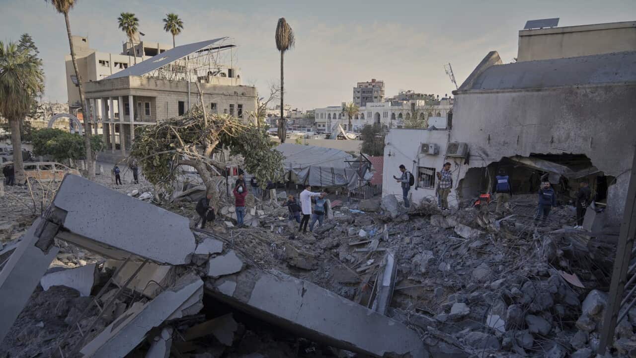 People stand amid the rubble of a destroyed building