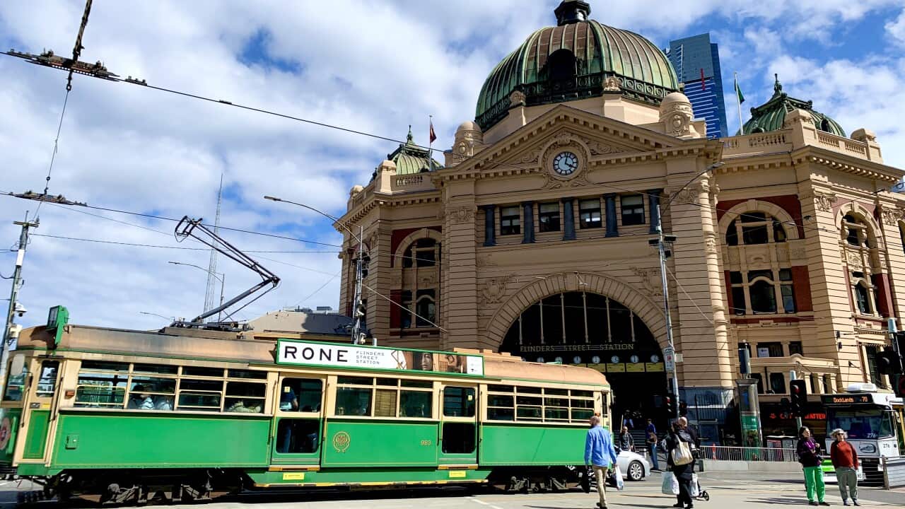A tram is passing in front of Melbourne Flinders Station. 