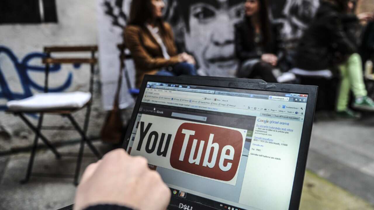 A person using a laptop computer showing YouTube's logo