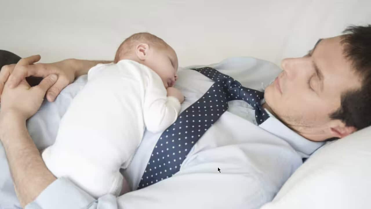 Working father lies sleeping with two week old. Source: AAP / MOODBOARD/MOODBOARD