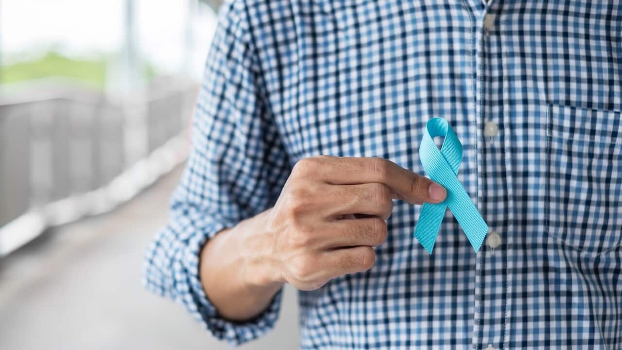 A man holding a blue ribbon for prostate cancer awareness