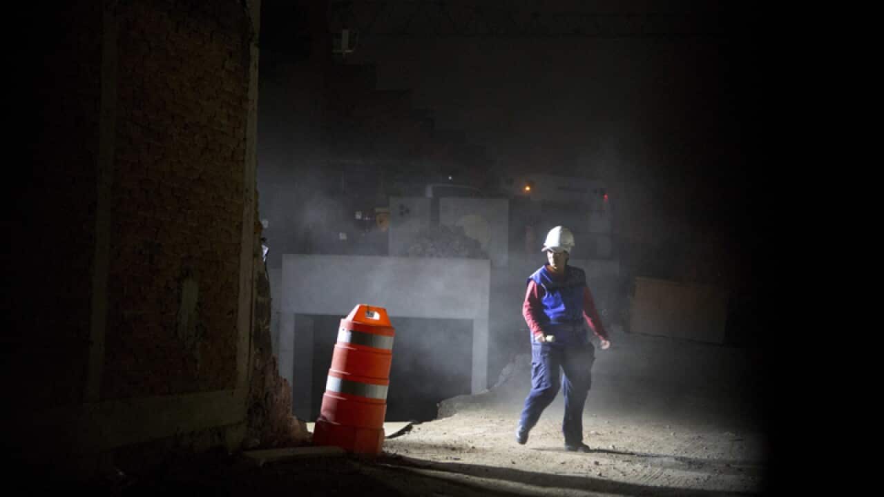 A rescue worker walks beside the scene of a building collapse