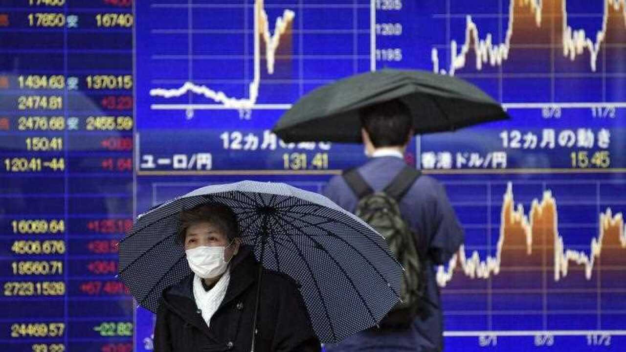 Pedestrians walk past a foreign currency indicator board in Tokyo,