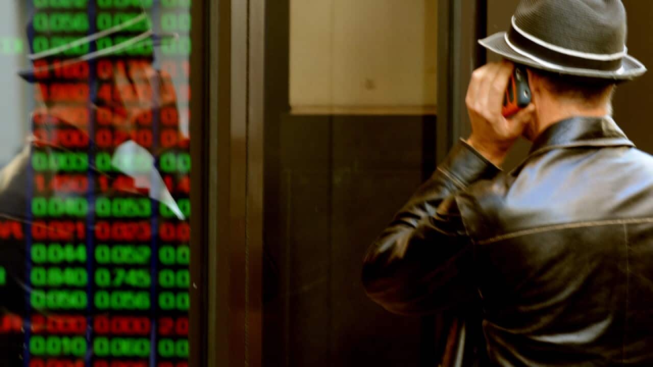 Man looks at electronic stock board.