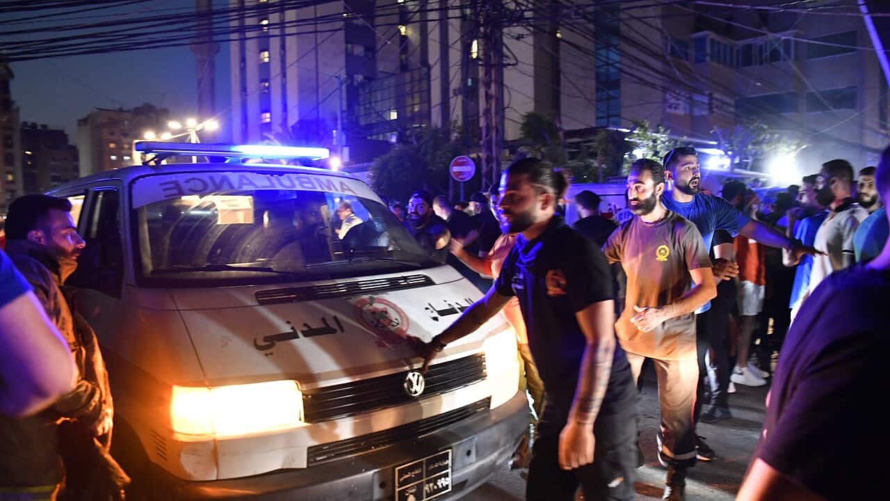An ambulance driving on a road, with people surrounding it.