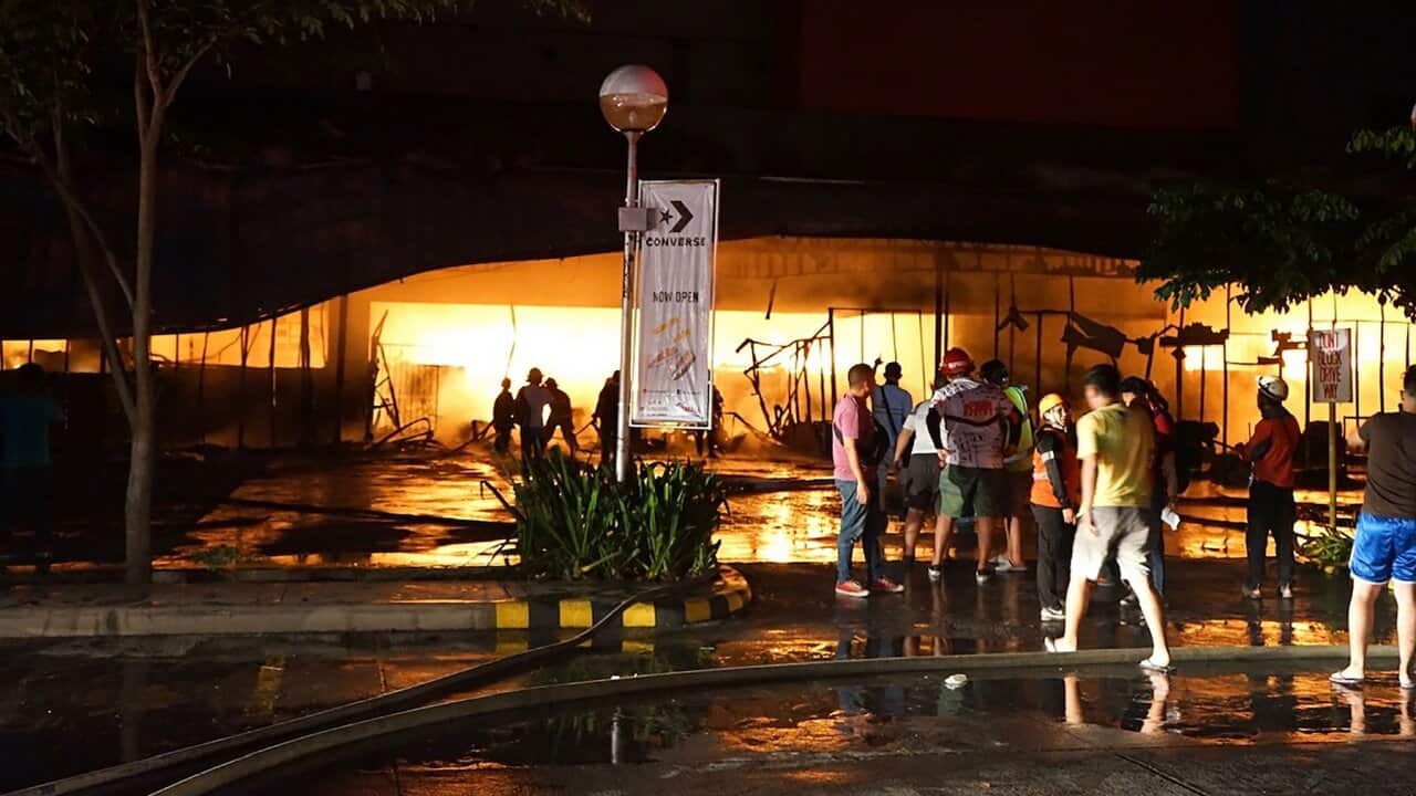 Firemen try to put out a fire on a mall following a 6.4-magnitude quake in General Santos City, in southern island of Mindanao, on October 16, 2019.