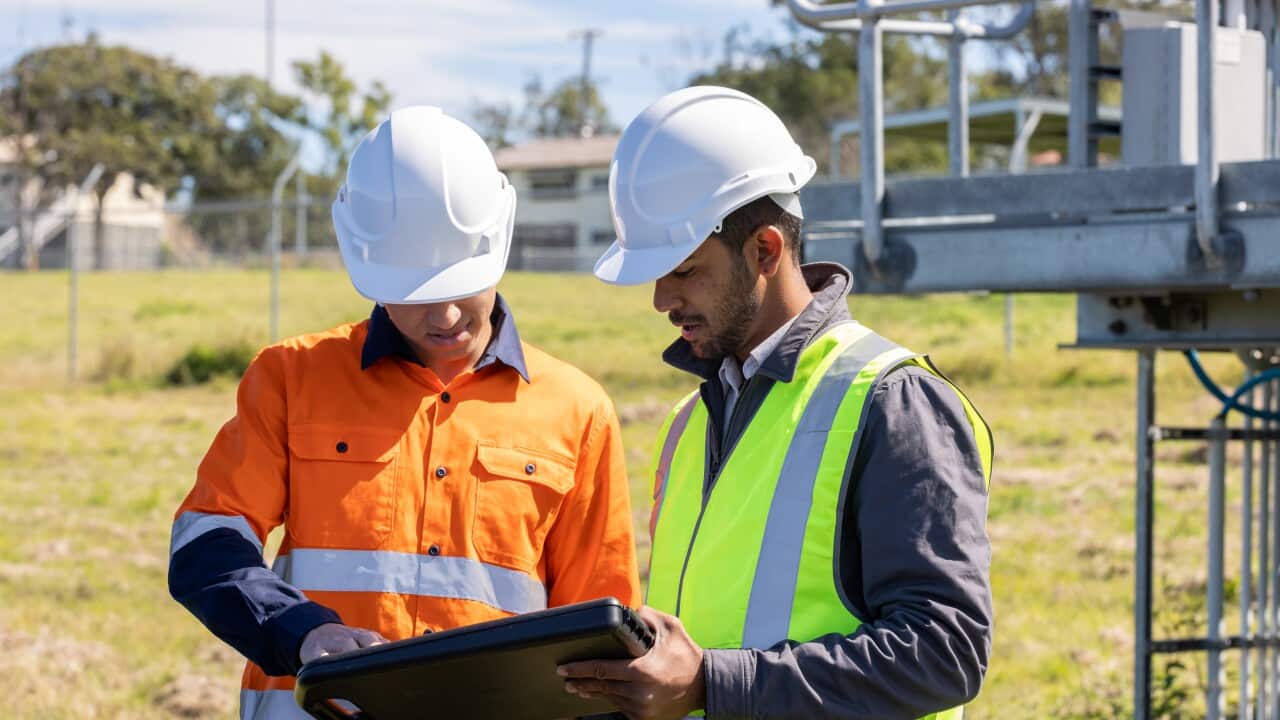 Indian-Australian Engineer and Aboriginal Australian Apprentice Working Together On Solar Farm Installation