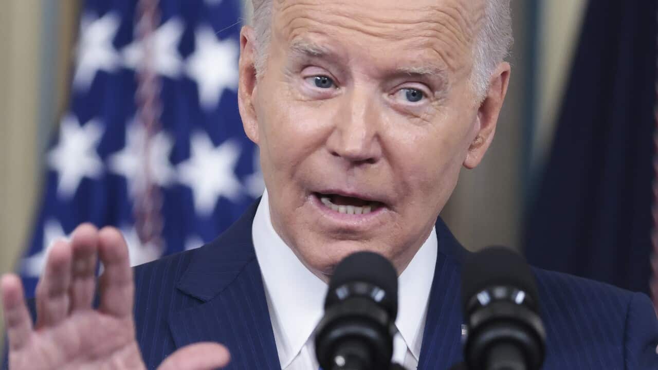 A man speaking in front of microphones while standing at a podium.