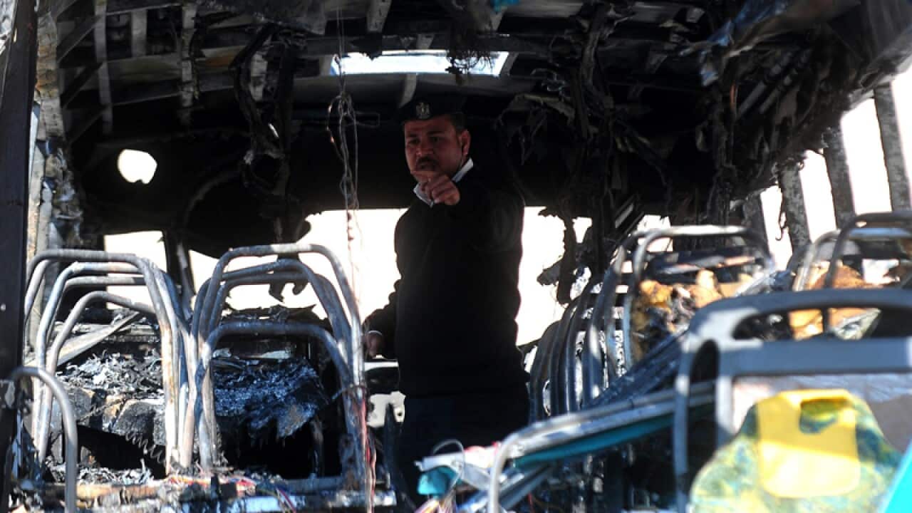 An Egyptian policeman stands inside a damaged tourist bus