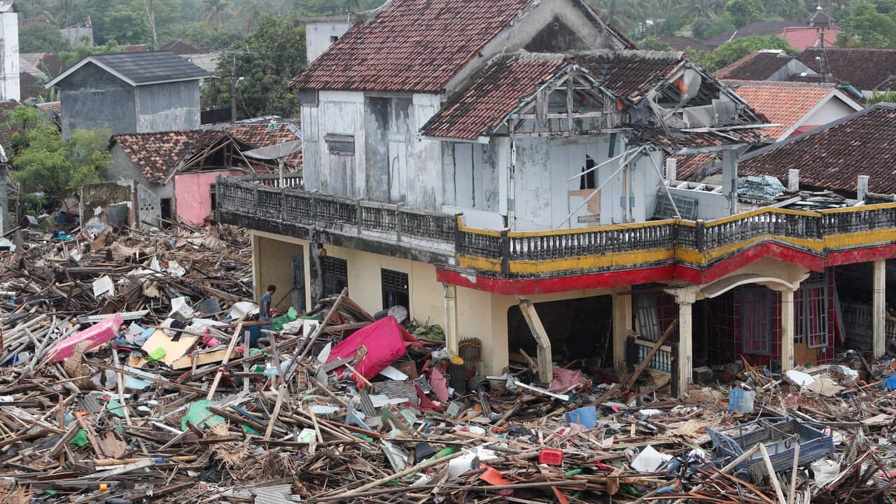 Local residents walk among debris in a devastated area after a tsunami hit Sunda Strait in Sumur, Banten, Indonesia.