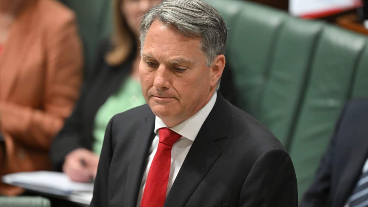 Richard Marles, wearing a black suit and red tie, standing on the floor of the House of Representatives.