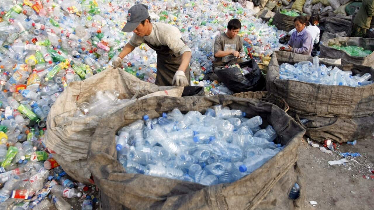 File image of Chinese workers sort through mounds of plastic bottles at a recycling centre in Beijing, China