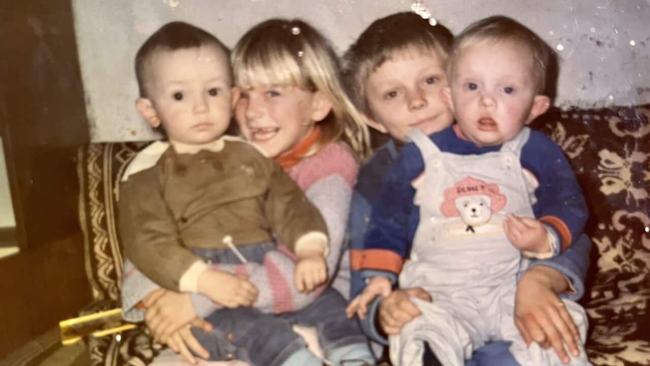 Four children are seated on a printed couch