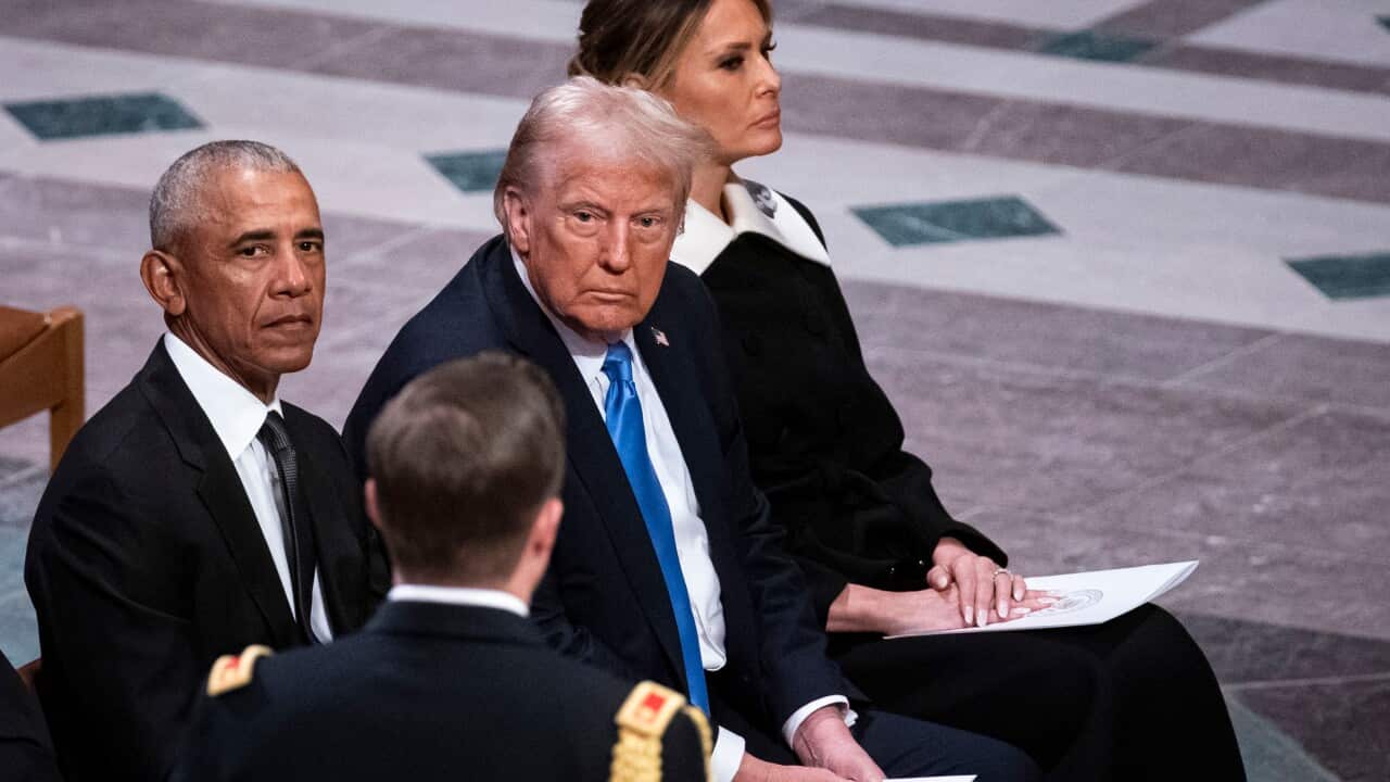 A middle-aged black man sitting beside an older white man and middle-aged white woman at a funeral