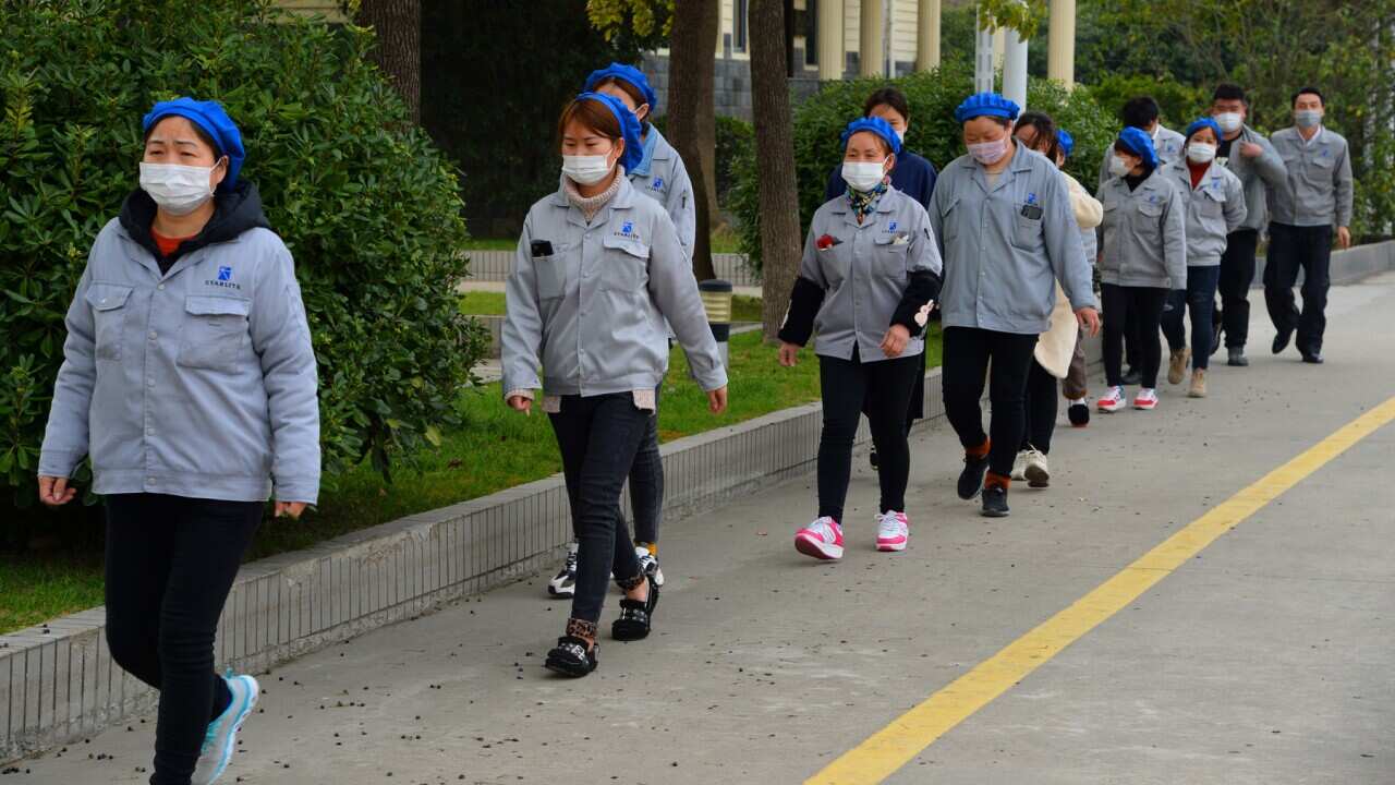 Masked female Chinese workers walk alone and separately for prevention of the novel coronavirus.