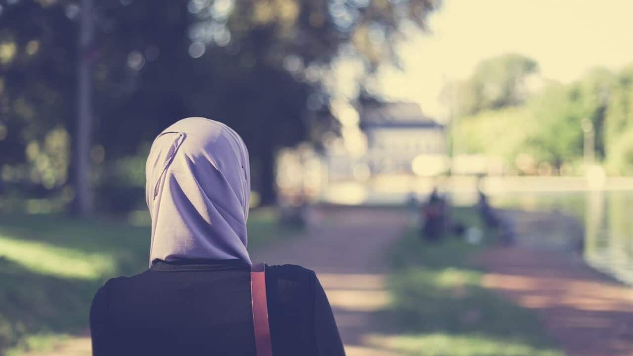 Rear view of a veiled muslim woman walking in forest
