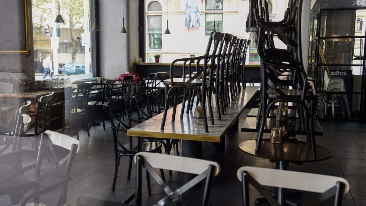 Stacked tables and chairs are seen in a closed Sydney cafe