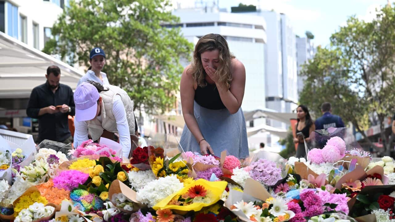 Woman cries over a splay of flowers. 