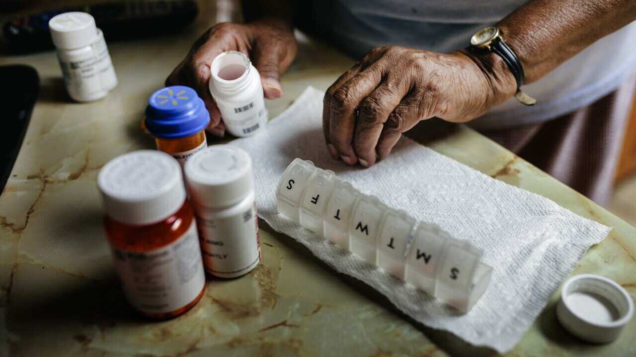 An older person sorting her medicines for the week