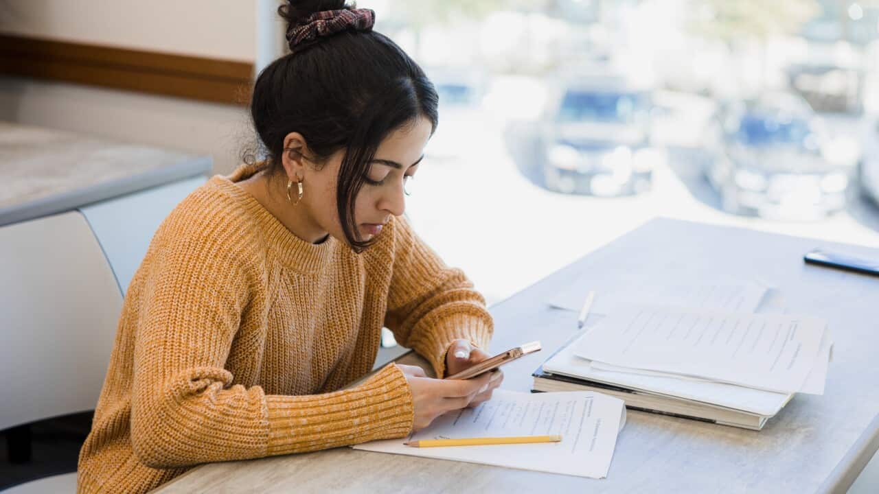 Young woman uses phone to find answers for test