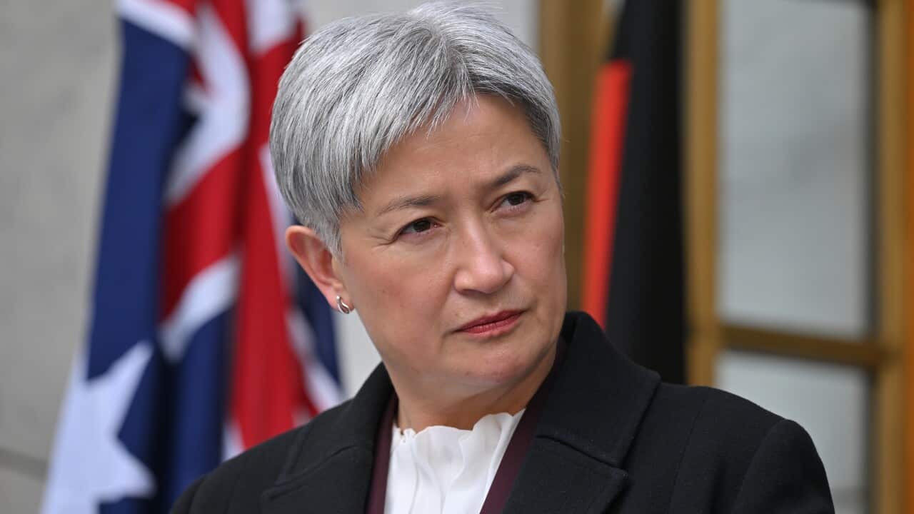 A woman in a suit in front of an Australian flag