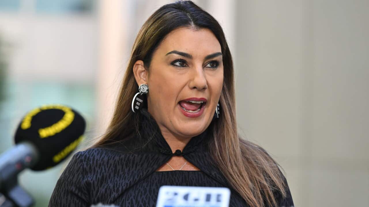 A woman speaking in front of microphones.