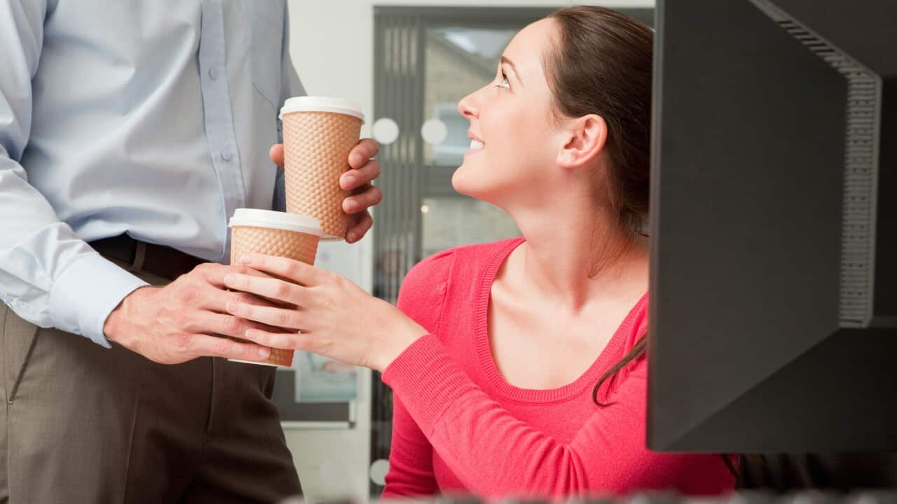 A male colleague brings a female colleague a coffee
