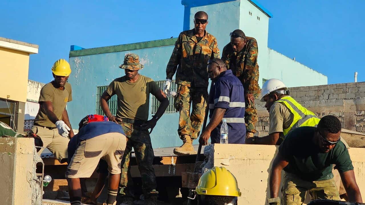 Men in military uniform searching through rubble.