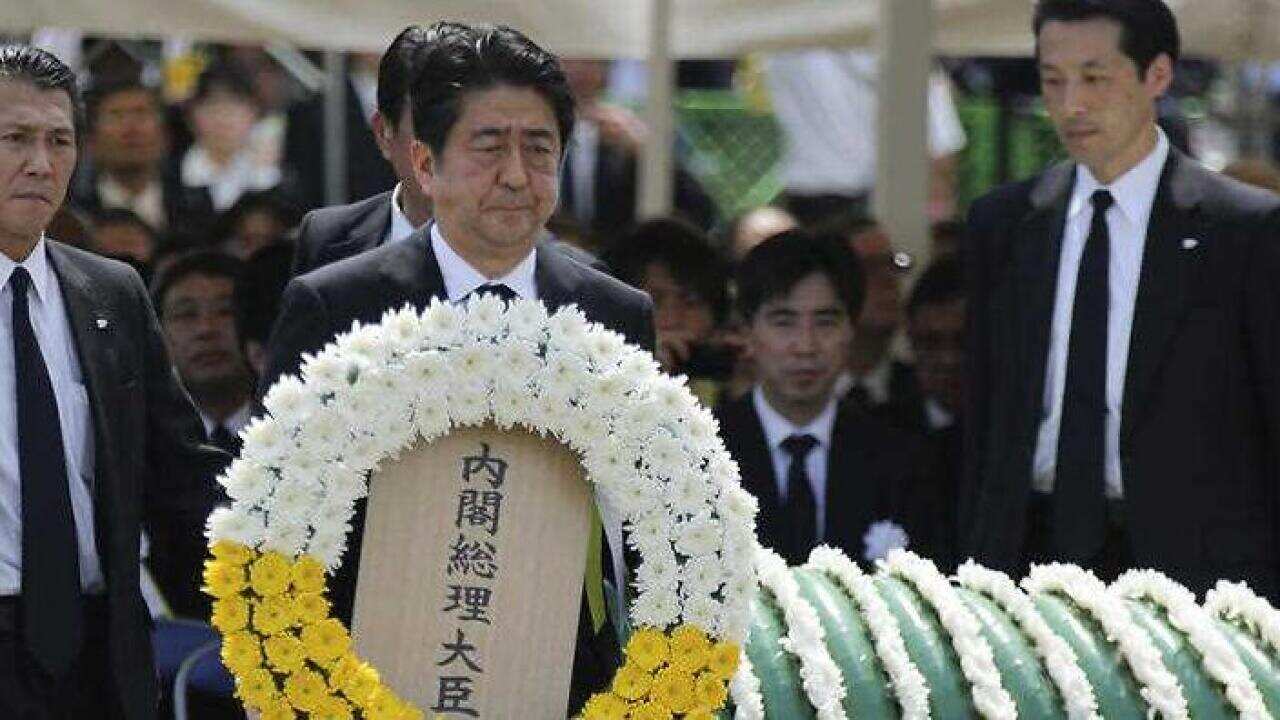 Japanese Prime Minister Shinzo Abe holds a wreath during a ceremony to mark the 70th anniversary of the Nagasaki atomic bombing in Nagasaki, southern Japan Sunday, Aug. 9, 2015. (AAP)