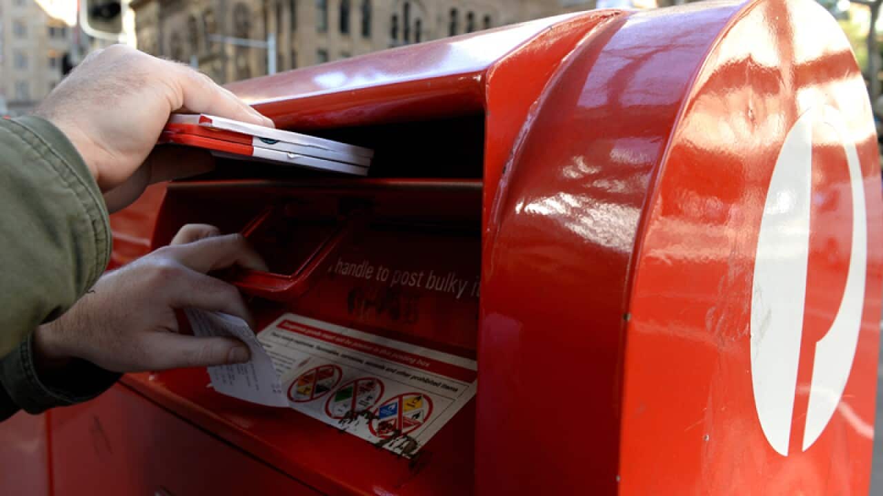 A man posting mail at an Australia Post postbox in Sydney,