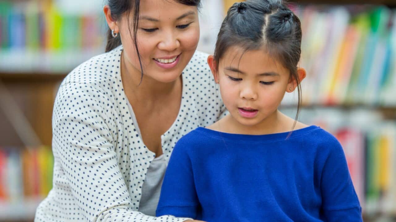 An Asian mother helping her daughter learn to read.