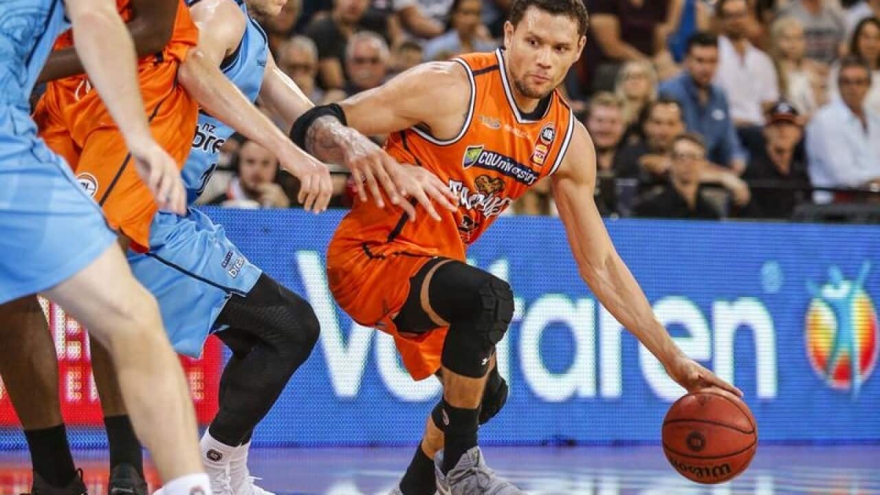 Michael Carrera (r) of the Taipans dribbles the ball past defender.