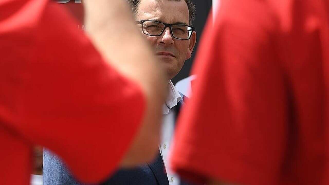 Premier Daniel Andrews between two red shirted Labor volunteers.