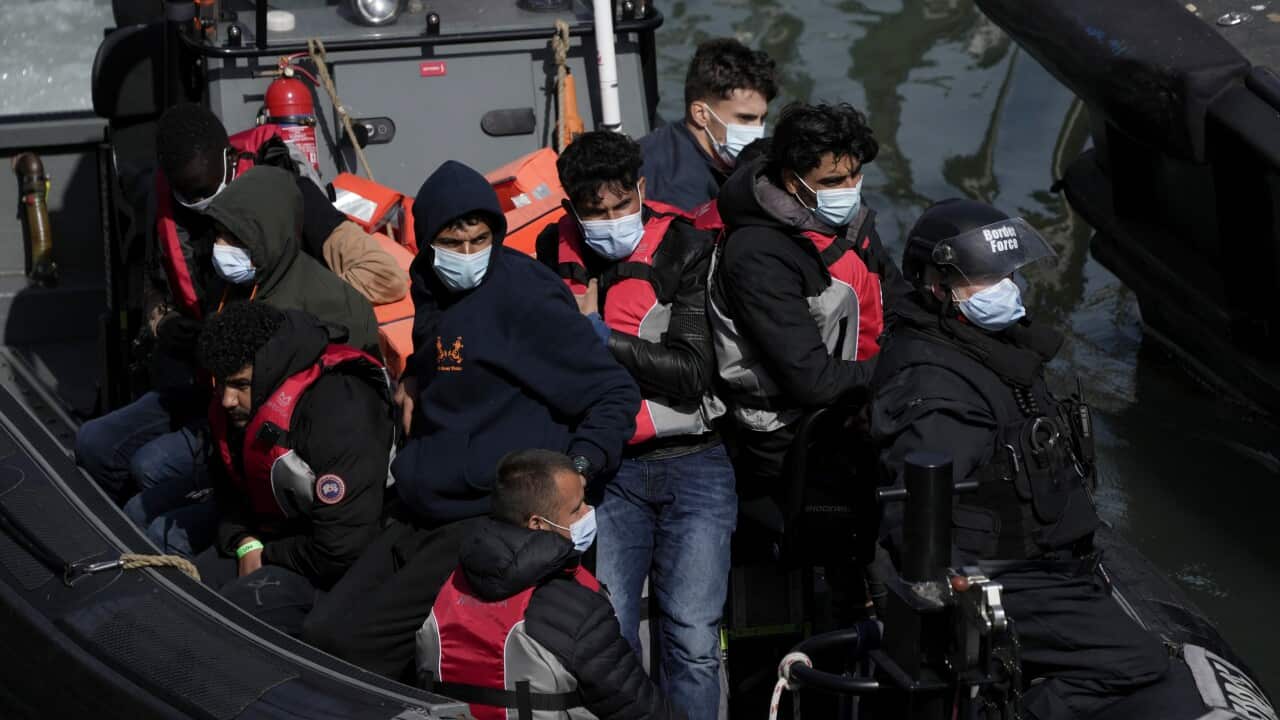 Asylum seekers wearing life jackets and face masks in a border force boat