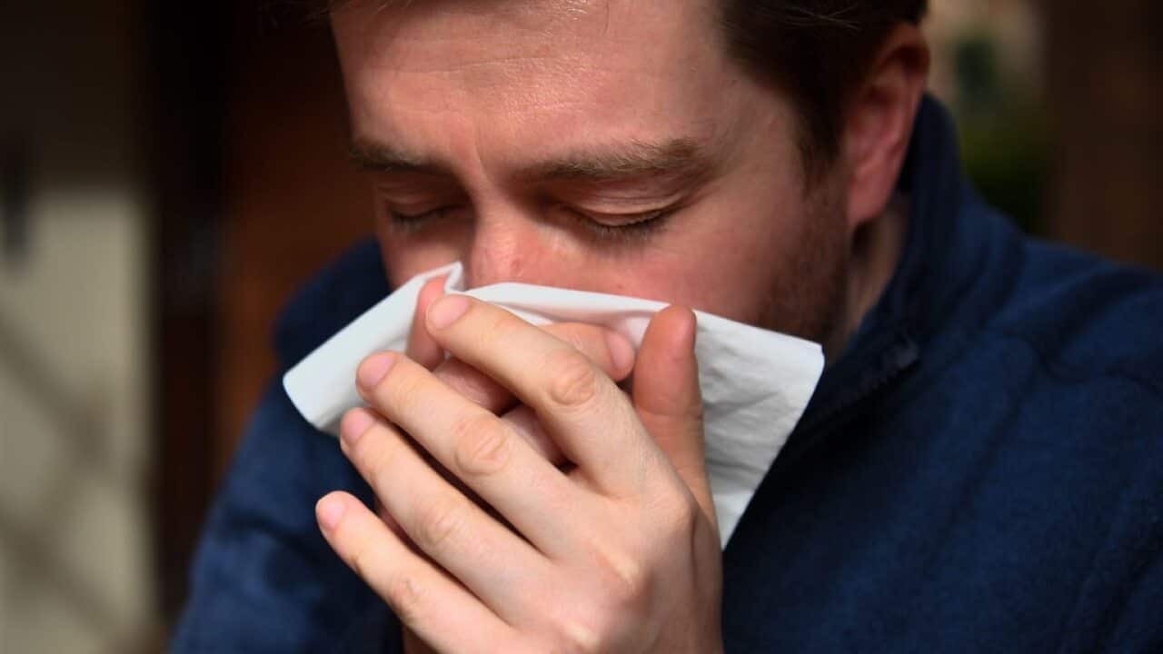 A man sneezes into a tissue.