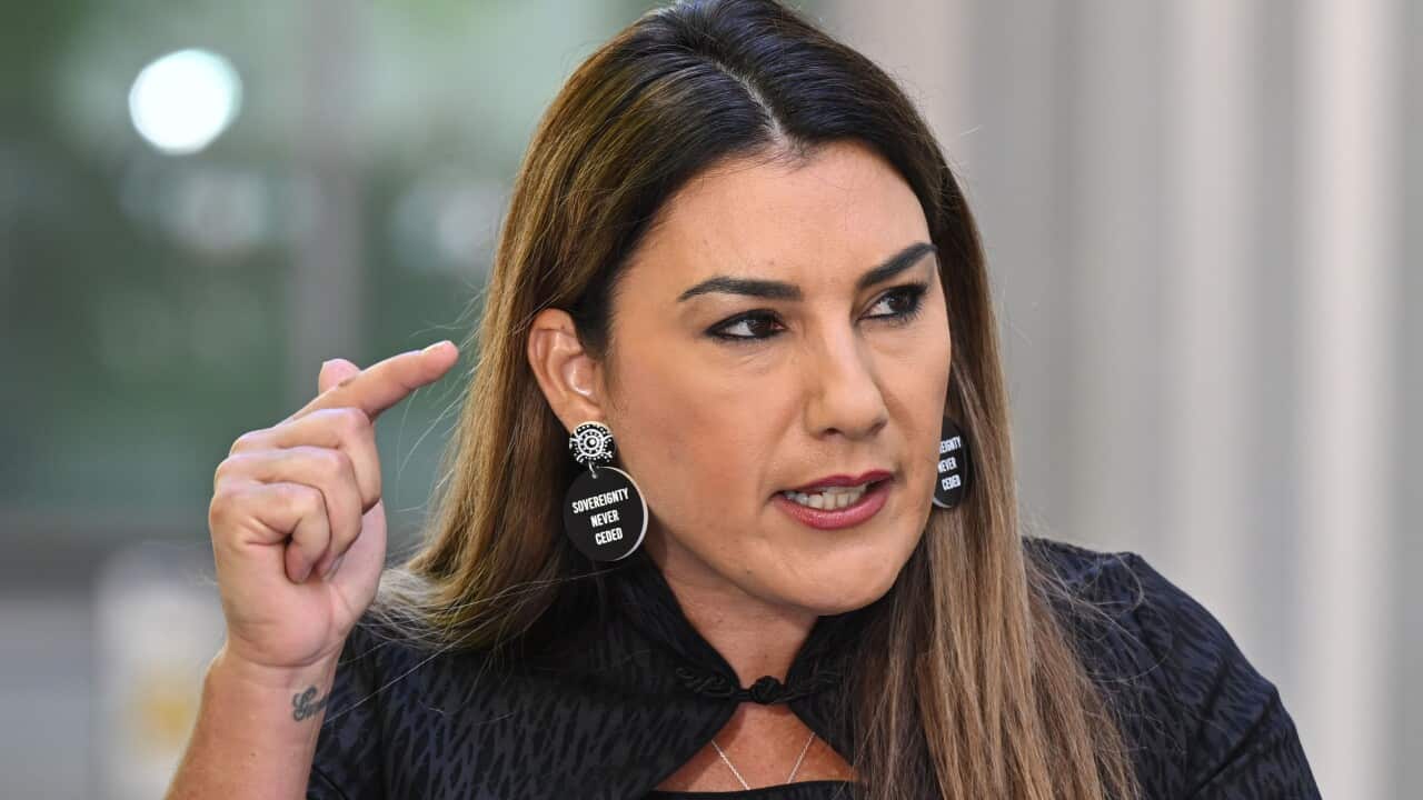 lidia thorpe gestures pointedly, wearing a black top and black earrings bearing the words “Sovereignty never ceded“