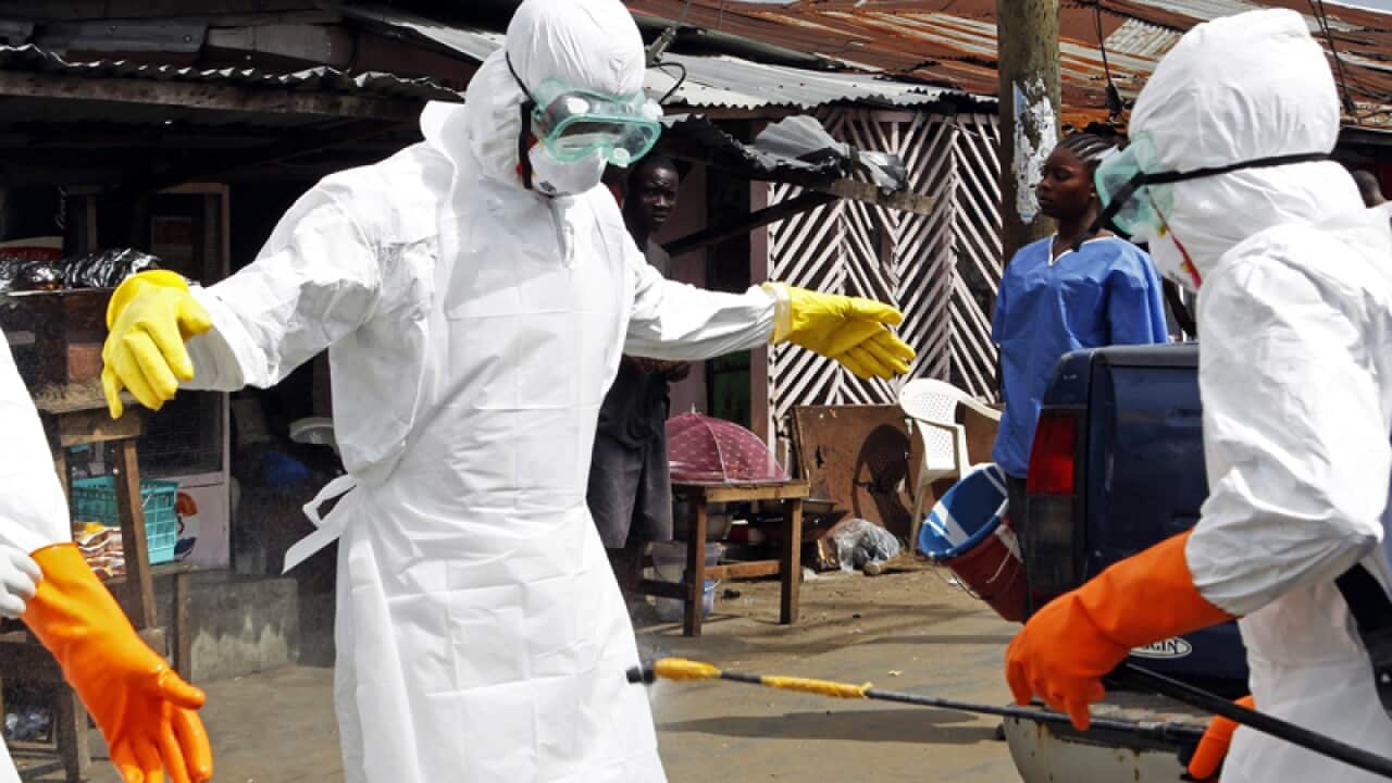 Healthcare workers disinfect one another.