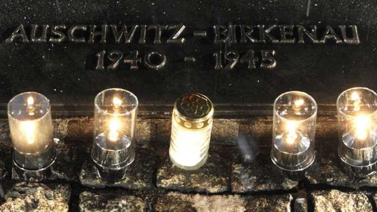 Candles burn by a memorial plaque at the Birkenau Nazi death camp in Poland