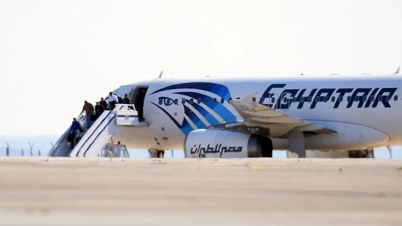 Passengers leave an EgyptAir Airbus A-320 sitting on the tarmac of Larnaca airport after it was hijacked and diverted to Cyprus on March 29, 2016.