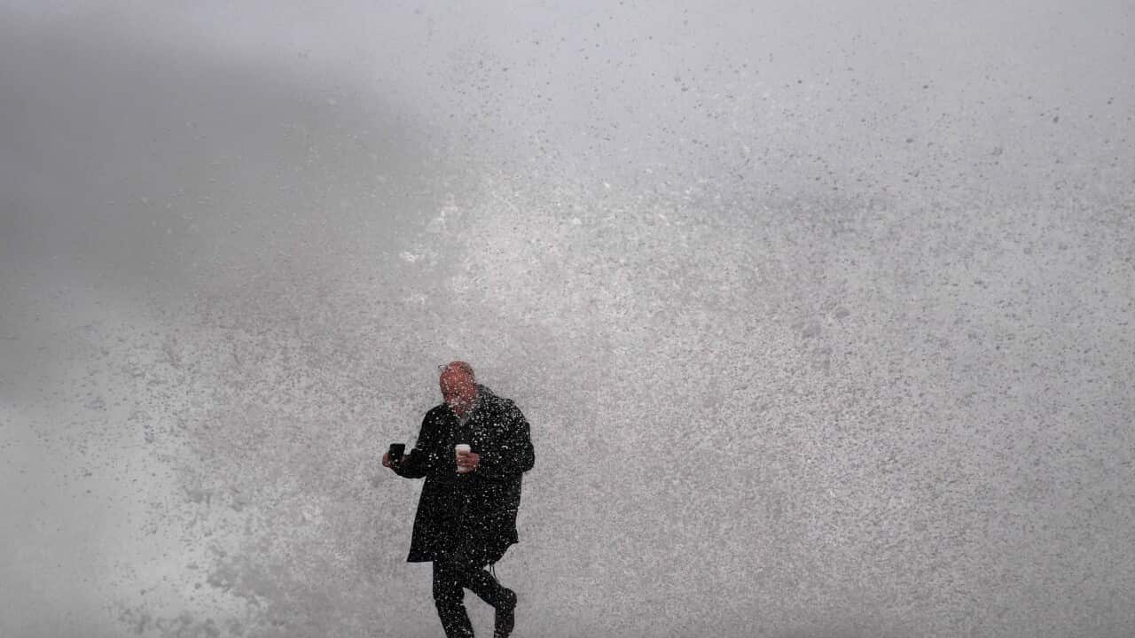 A man is engulfed by a breaking wave as he walks along the cliff top at Clovelly Beach in Sydney.