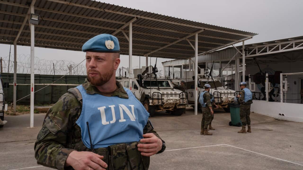 A man in military uniform is wearing a blue beret and an apron with UN written on it.