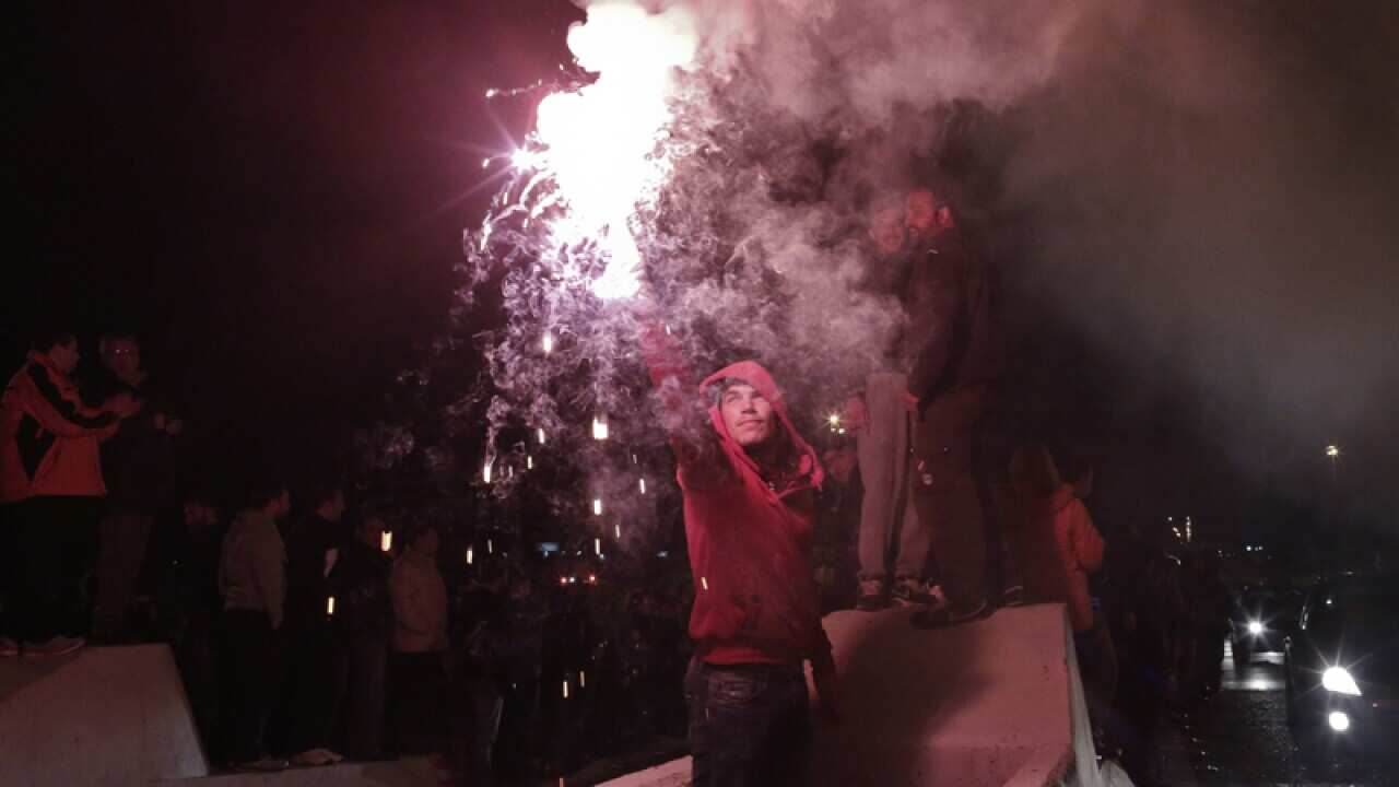 A protester holds a flare as others raise the bars at a toll station